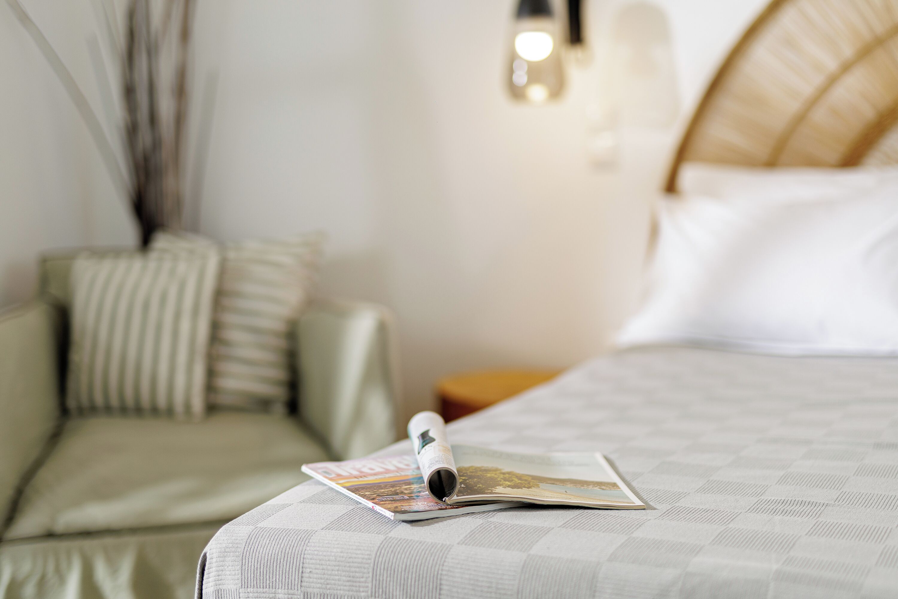 A neatly made bed with a checkered bedspread, a pillow, and a magazine on the bed.