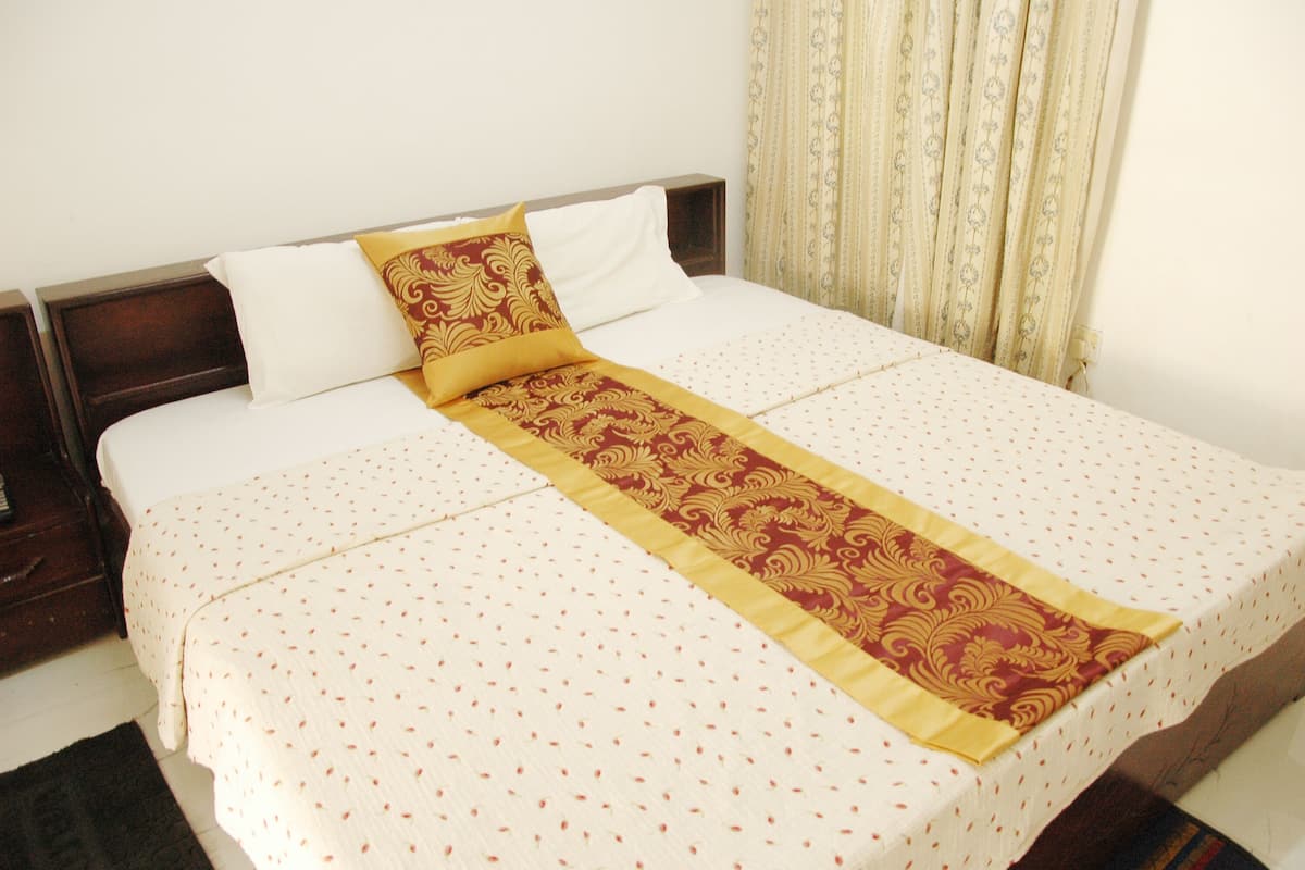 A neatly made bed with a patterned bedspread and a decorative runner.