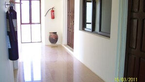 A hallway with a fire extinguisher, a vase, and a door. - Pekan Hotel (Accra)