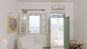 Ein Zimmer mit einem Bett, einem Fenster mit Blick, einer Tür und einer Wand-Klimaanlage.