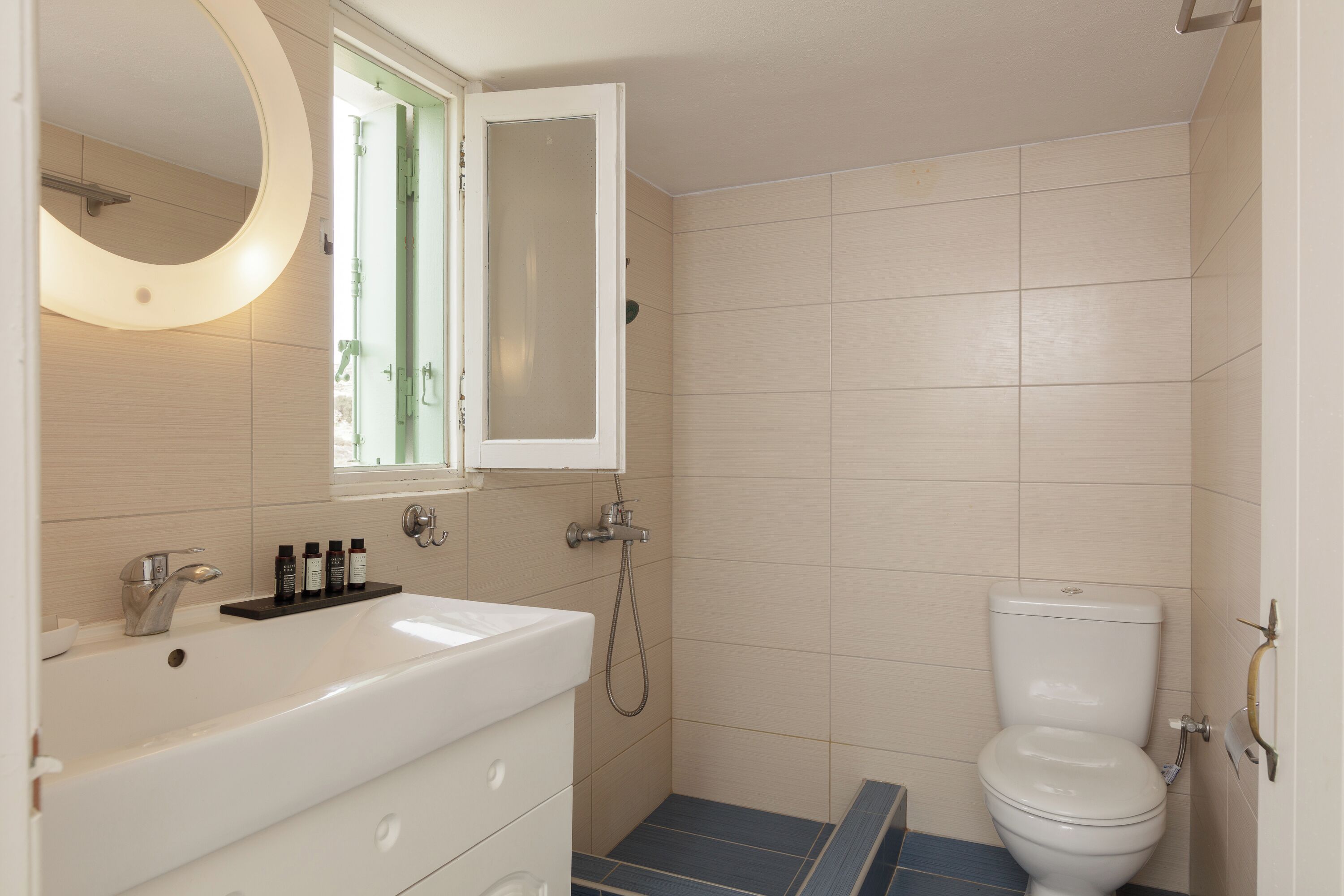 A bathroom with a white sink, mirror, and toilet.