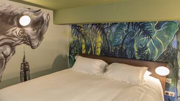 A hotel room with a large bed, a mural of a horse and the Empire State Building, and a tropical leaf pattern on the wall.