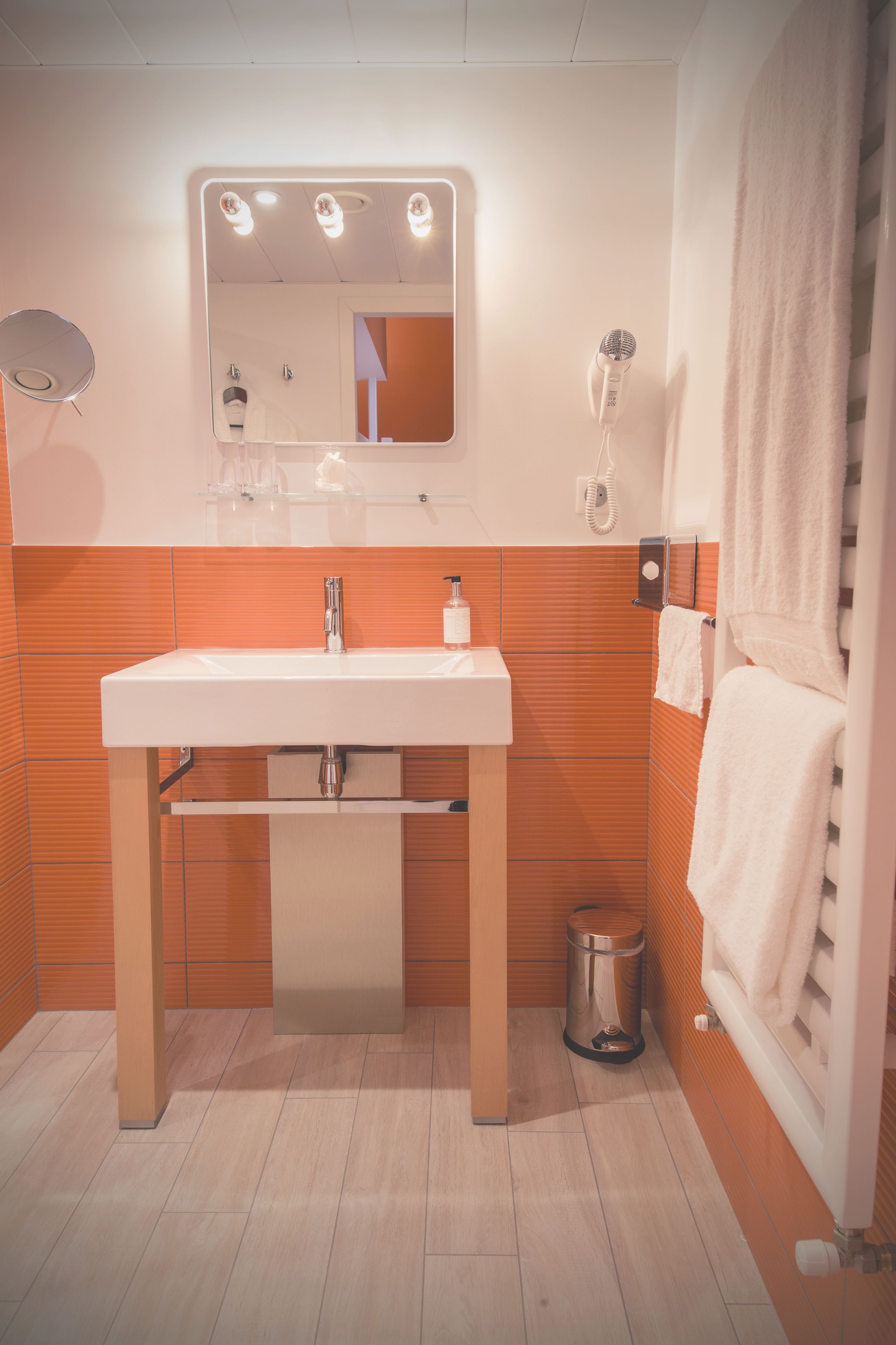 Un baño con lavamanos blanco, espejo y toallero.