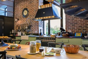 A kitchen with a brick wall, a clock, and various kitchen items on the counter. - Le Magic Hall (Rennes)
