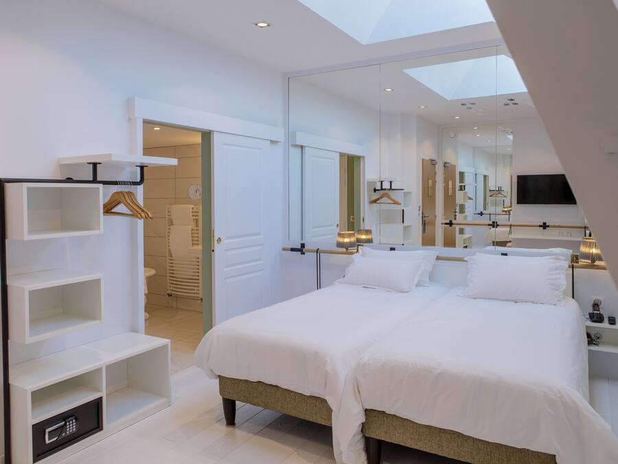 Un dormitorio moderno con tragaluz, cama grande, estanterías empotradas y vestidor.