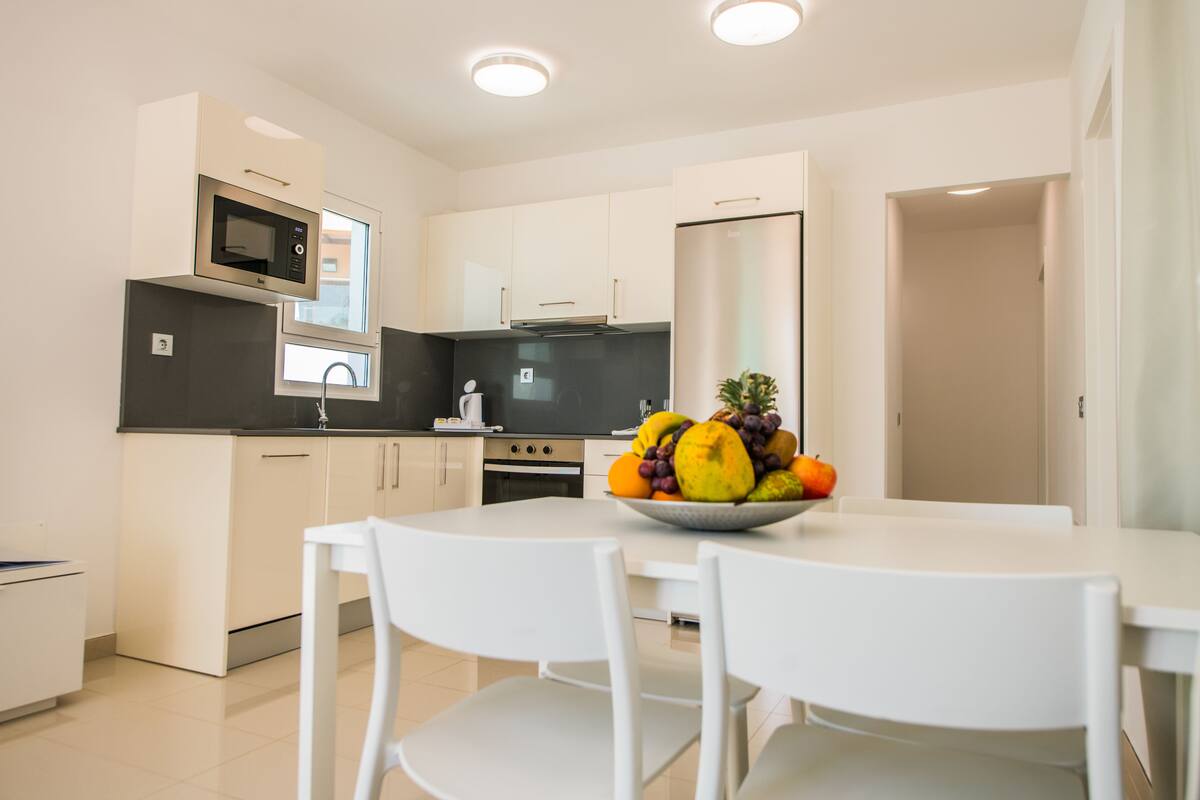 A modern kitchen with white cabinets, a built-in microwave, and a stainless steel refrigerator.