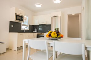 A modern kitchen with white cabinets, a built-in microwave, and a stainless steel refrigerator. - Bahía Calma Beach (Pajara)