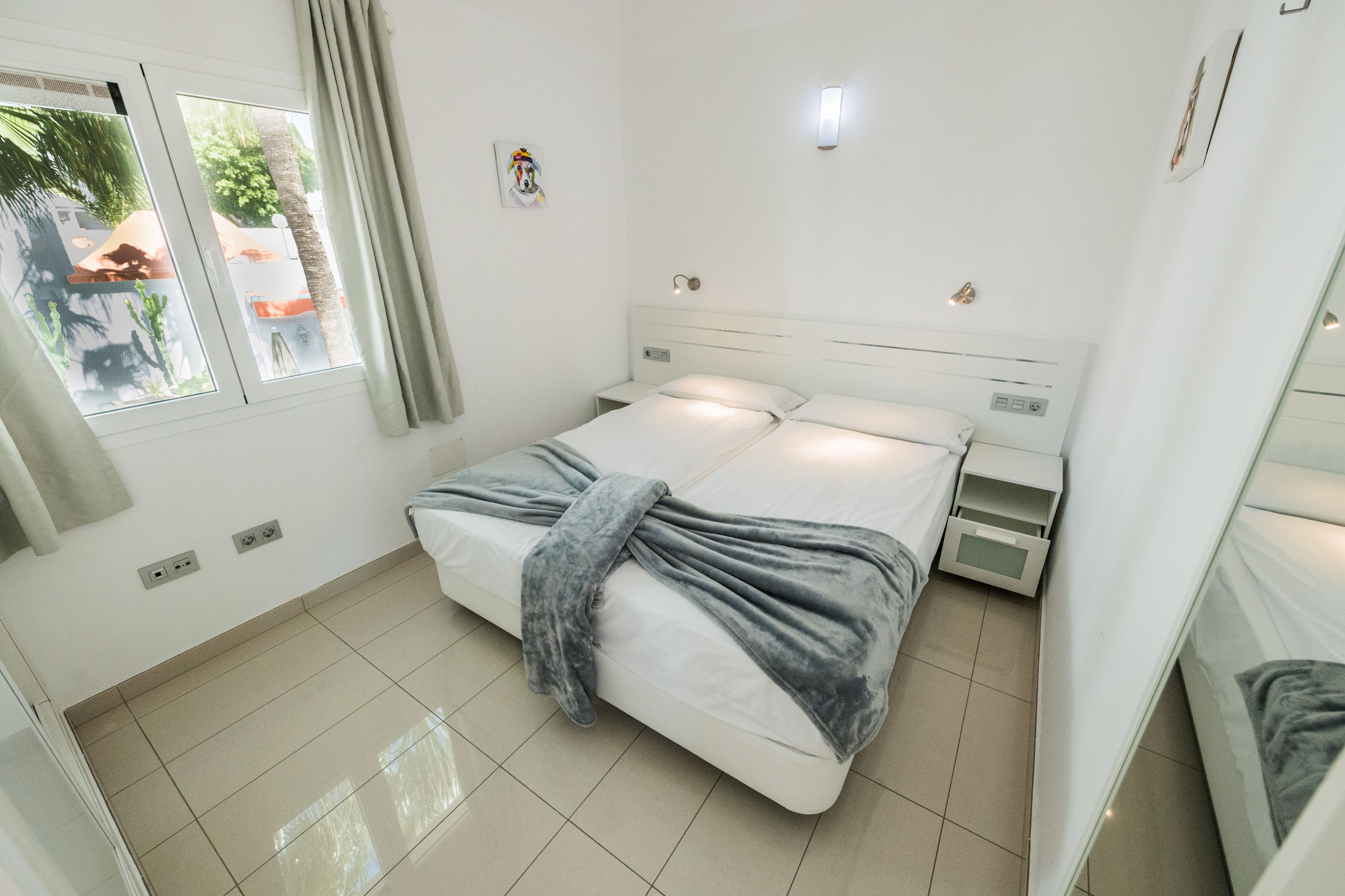 A modern bedroom with a bed, bedside tables, and a window with curtains.