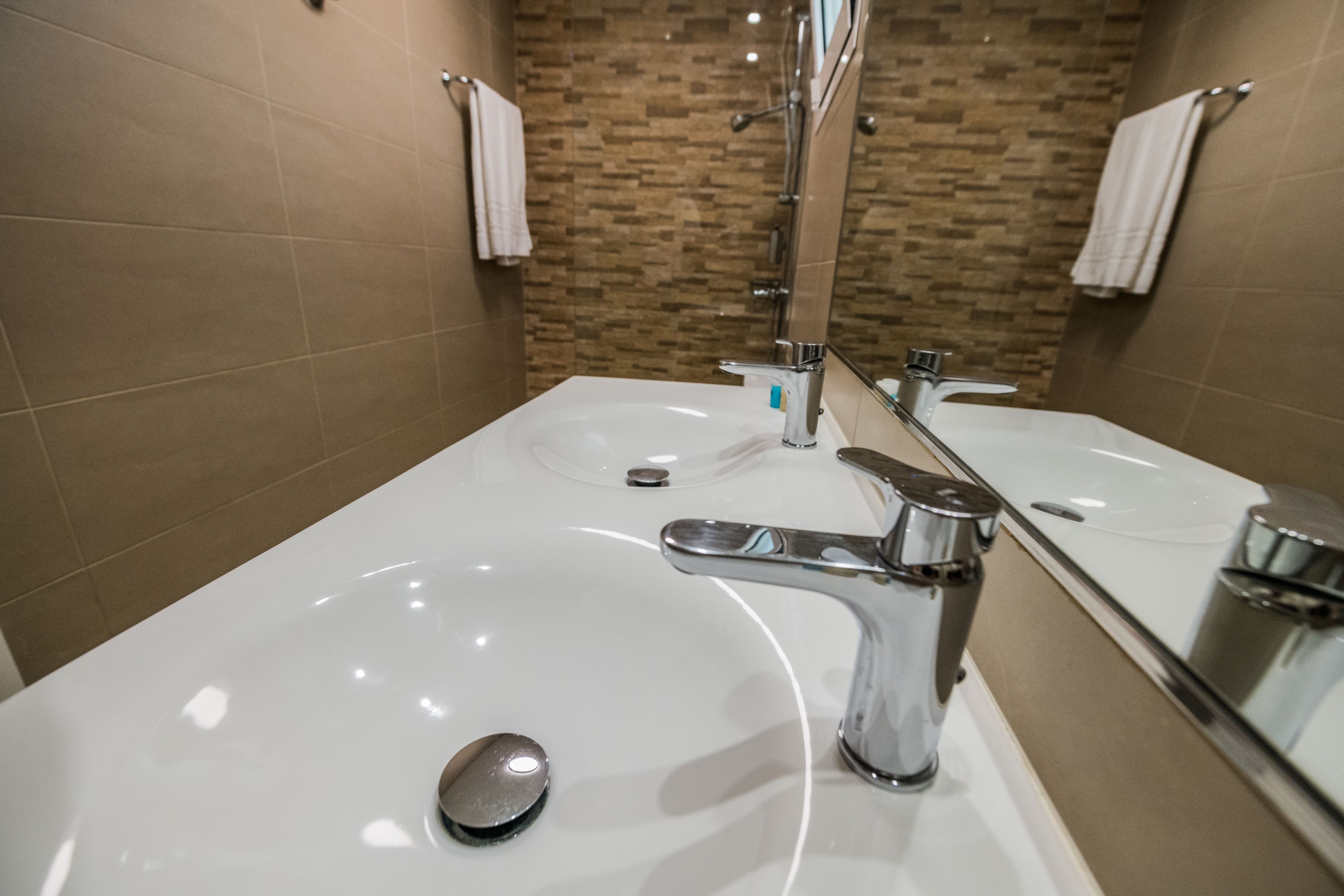 A bathroom with two sinks, a mirror, and a shower.