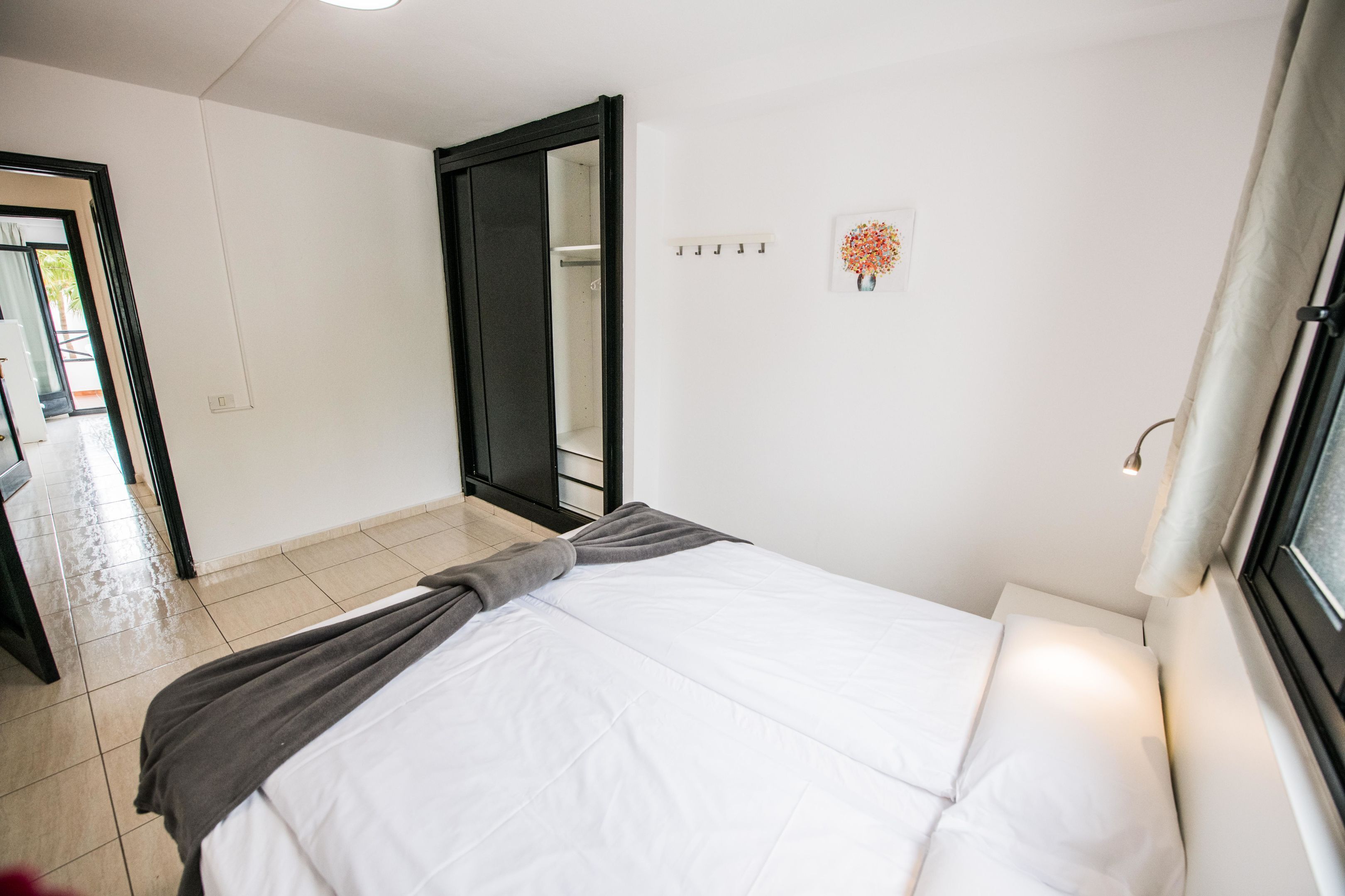 Un dormitorio con cama, espejo, ventana y puerta.