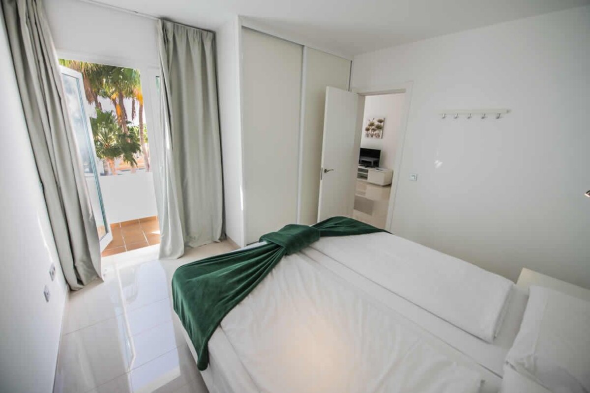 A hotel room with a bed, a desk, a chair, and a window with curtains.