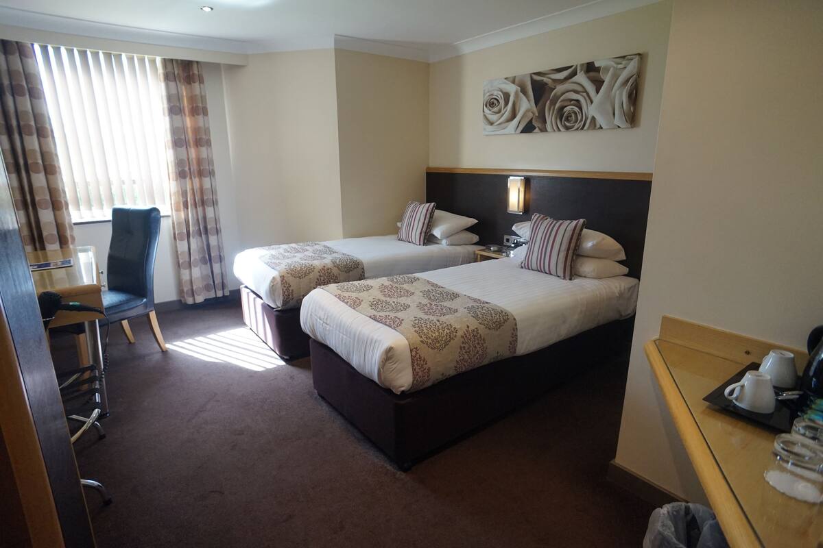 A hotel room with two beds, a desk, a chair, and a coffee table.