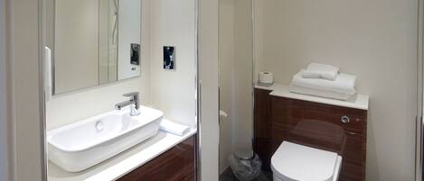 A modern bathroom with a white sink, mirror, and toilet.