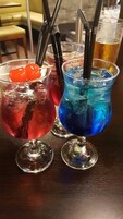 Dos cócteles con pajitas y cubitos de hielo en vasos sobre una mesa de madera.