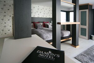 Una habitación de motel moderna con una litera, un escritorio y vista a otra habitación.