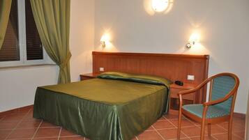 Une chambre à coucher comprenant un lit, une chaise, une table de chevet et deux lampes fixées au mur.