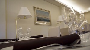 Ett hotellrum med ett välordnat matbord, två lampor och en inramad tavla på väggen.