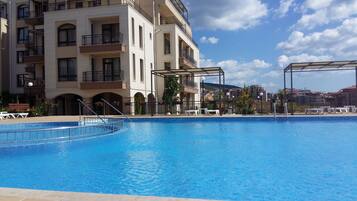 Relax by the pool with lounge chairs and umbrellas, surrounded by a multi-story hotel with balconies.