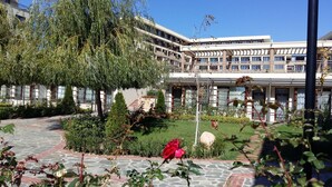 A courtyard with a stone pathway, a red rose, and a building with multiple floors and balconies.