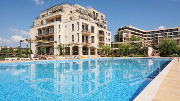 En säsongsöppen utomhuspool, bassäng med vattenfall och solstolar