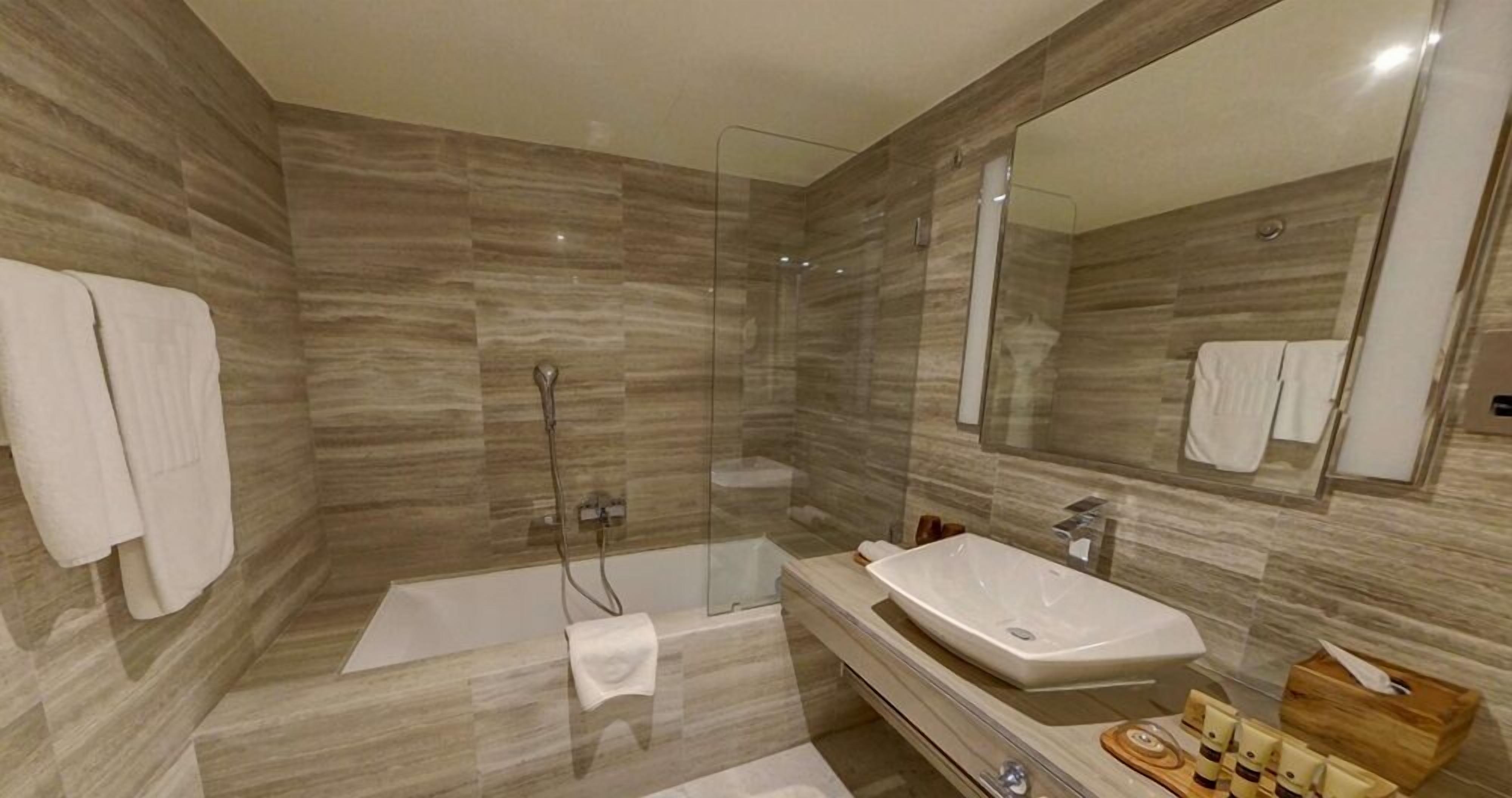 Une salle de bain moderne dotée d’une douche à parois de verre, d’un grand lavabo et d’un miroir.