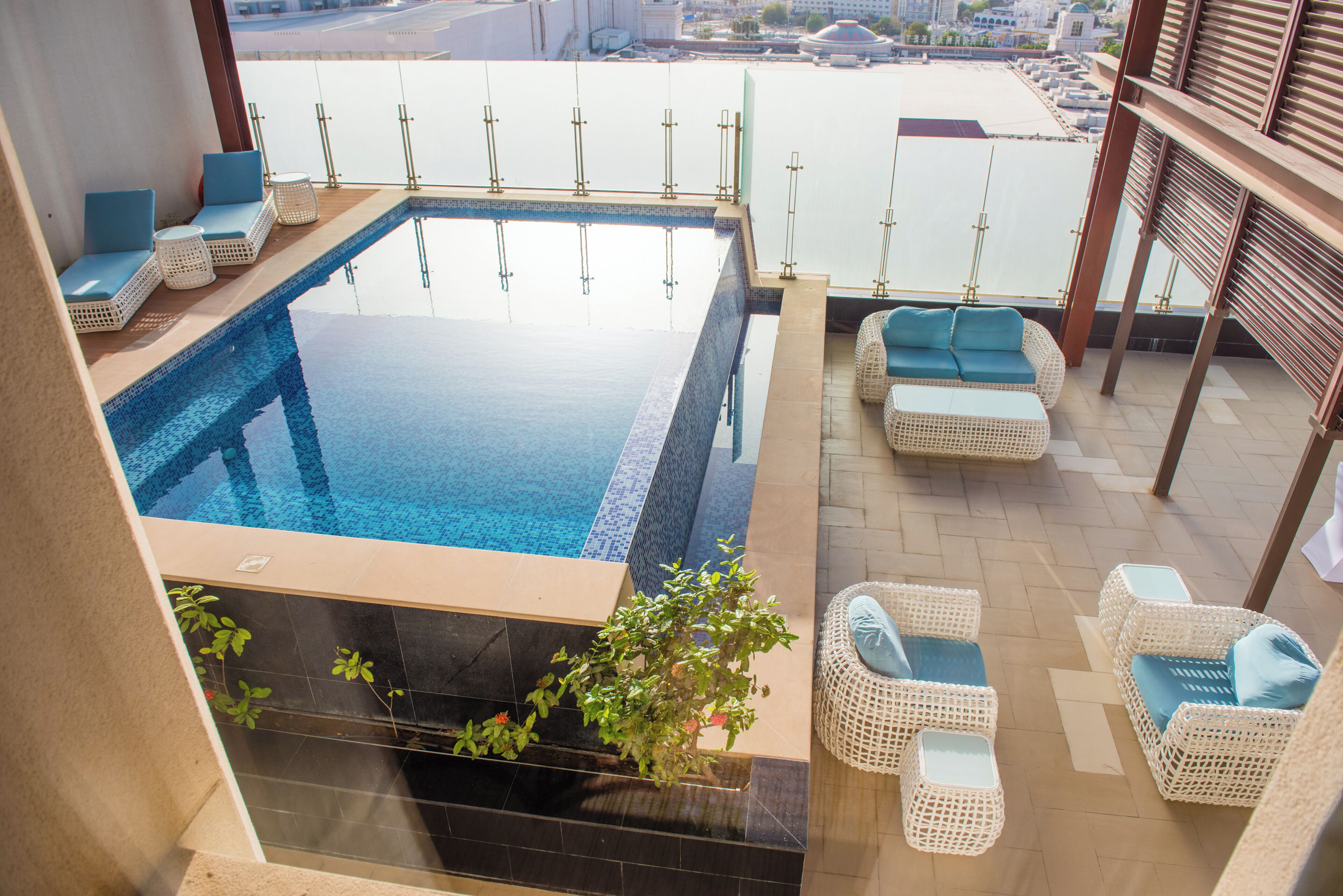A rooftop infinity pool with wicker furniture and a view of the city.