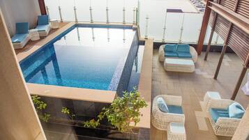 A rooftop infinity pool with wicker furniture and a view of the city.