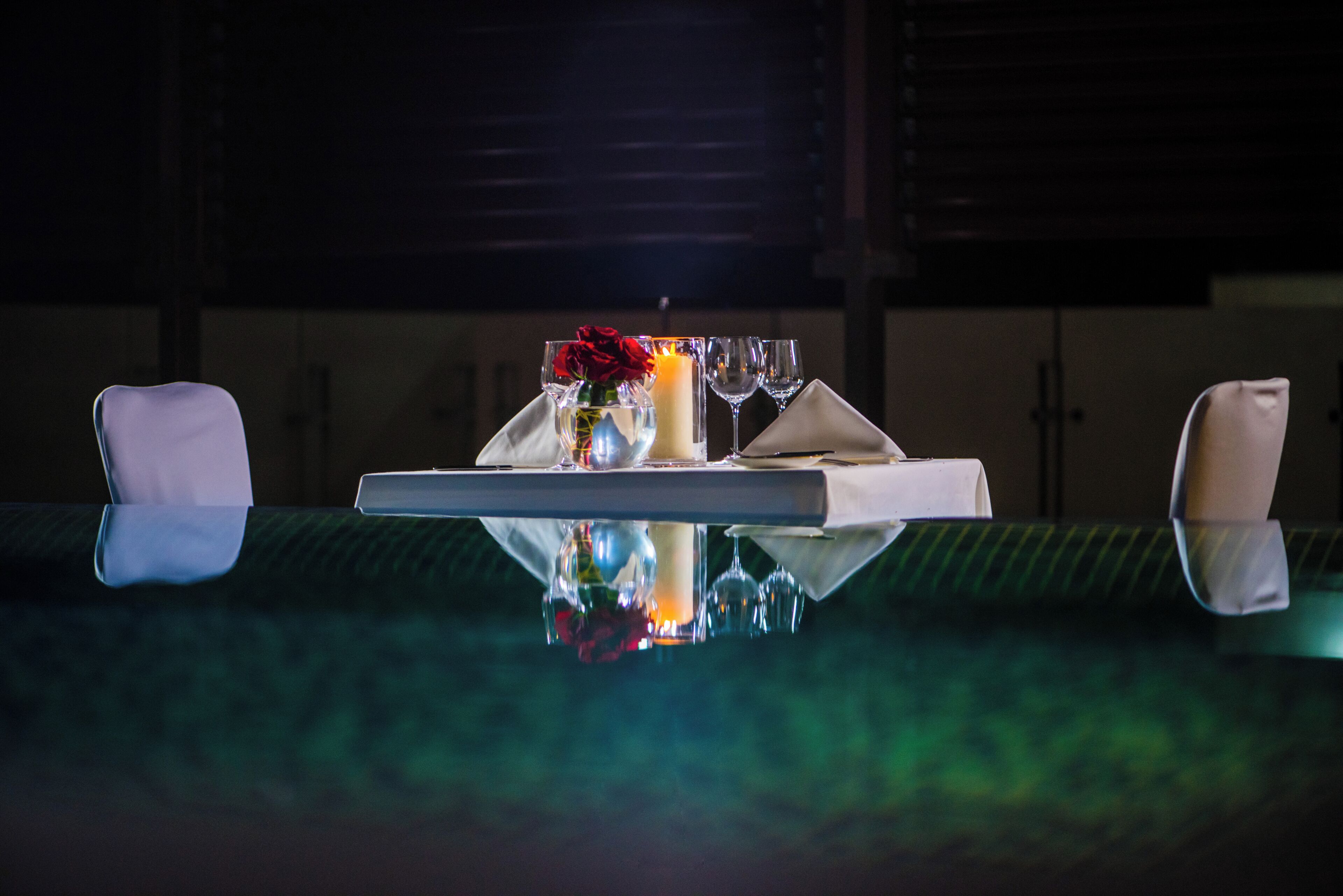 Una mesa de comedor con una vela, un vaso y un jarrón con flores.