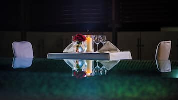 Una mesa de comedor con una vela, un vaso y un jarrón con flores.