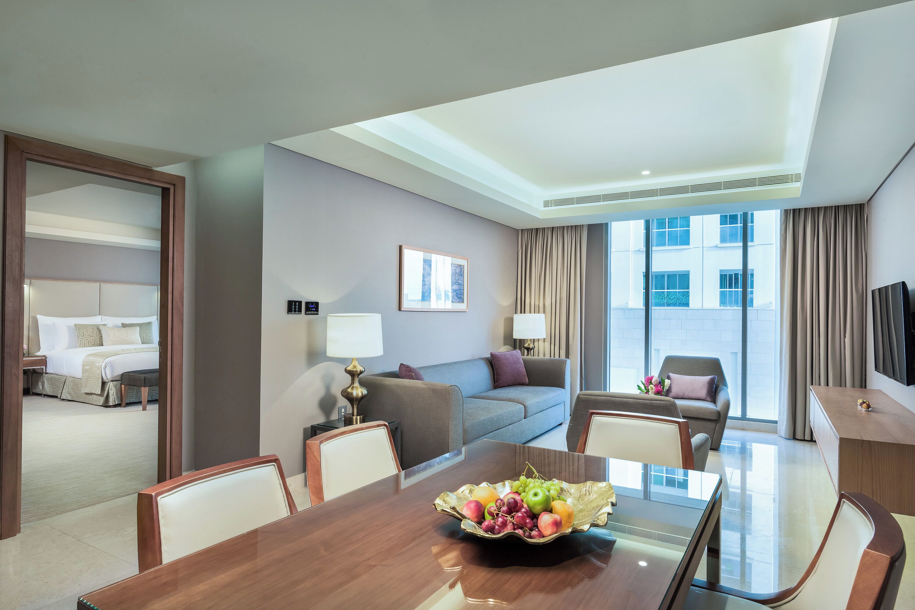 Une chambre d’hôtel équipée d’une table à manger, d’un canapé, d’une télévision et d’une grande fenêtre.