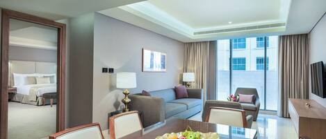 Une chambre d’hôtel équipée d’une table à manger, d’un canapé, d’une télévision et d’une grande fenêtre.