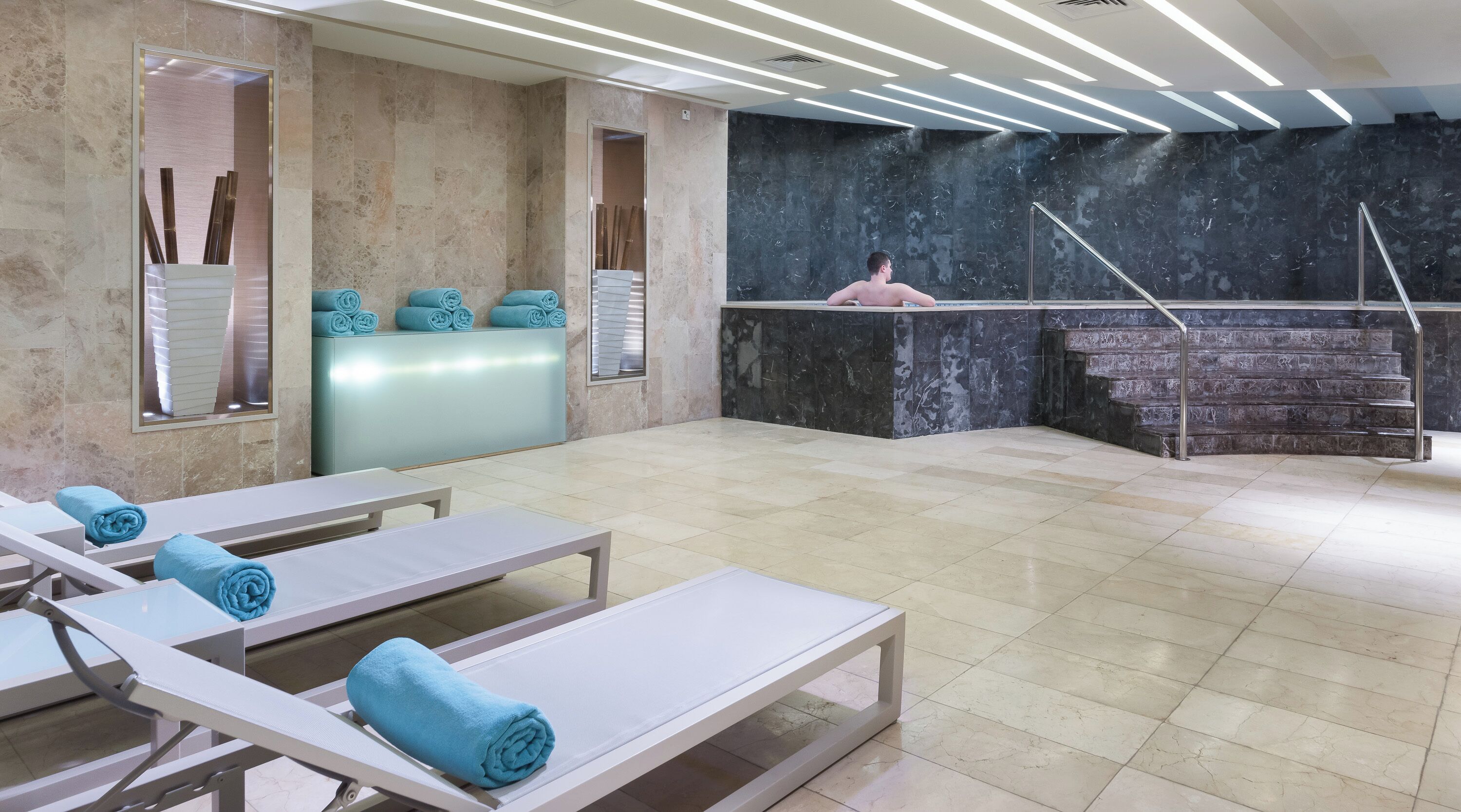 A spa area with massage tables, a reception desk, and a marble staircase.