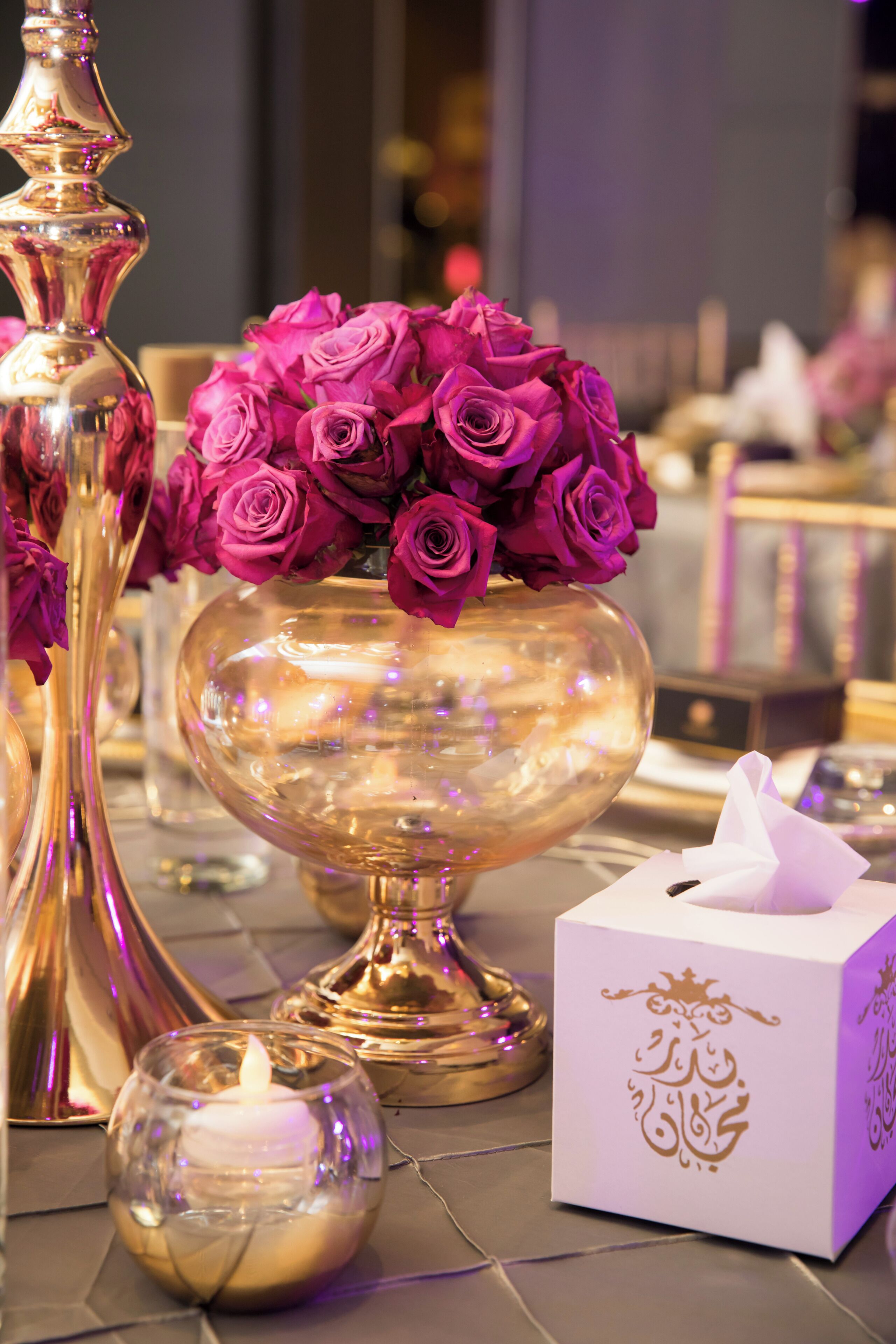 Ein Tisch mit einer goldenen Vase, einer brennenden Kerze und einer Schachtel mit arabischen Schriftzeichen.