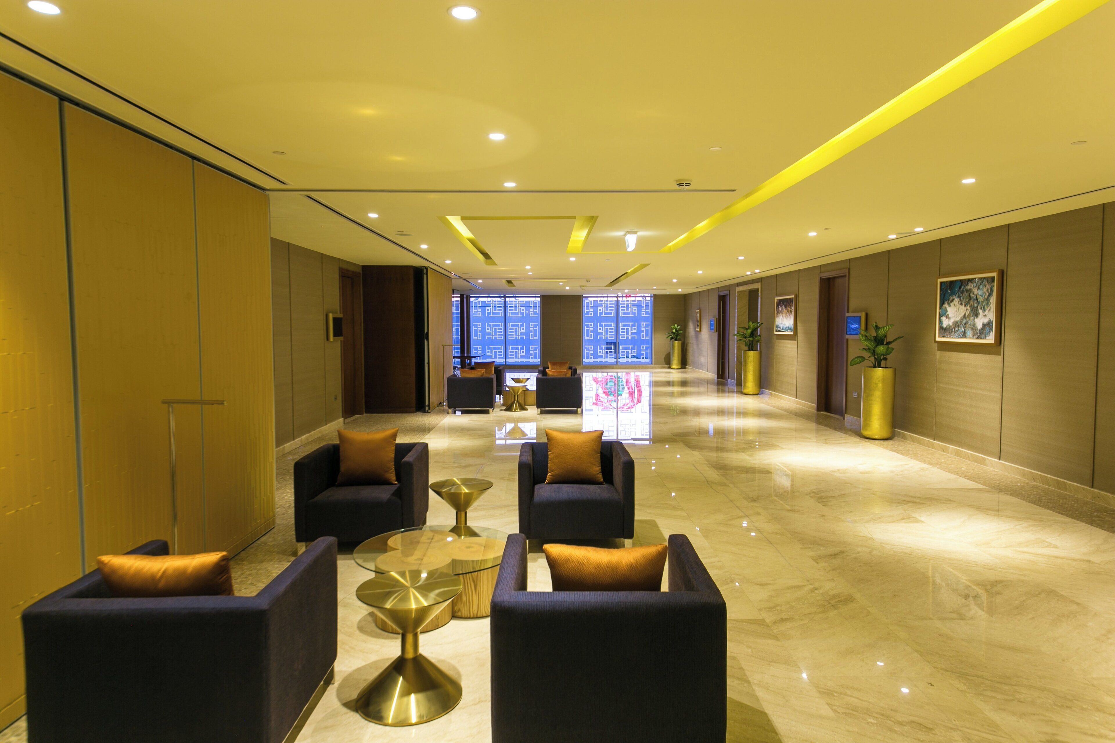 A modern lobby with seating areas, a reception desk, and a large digital display.