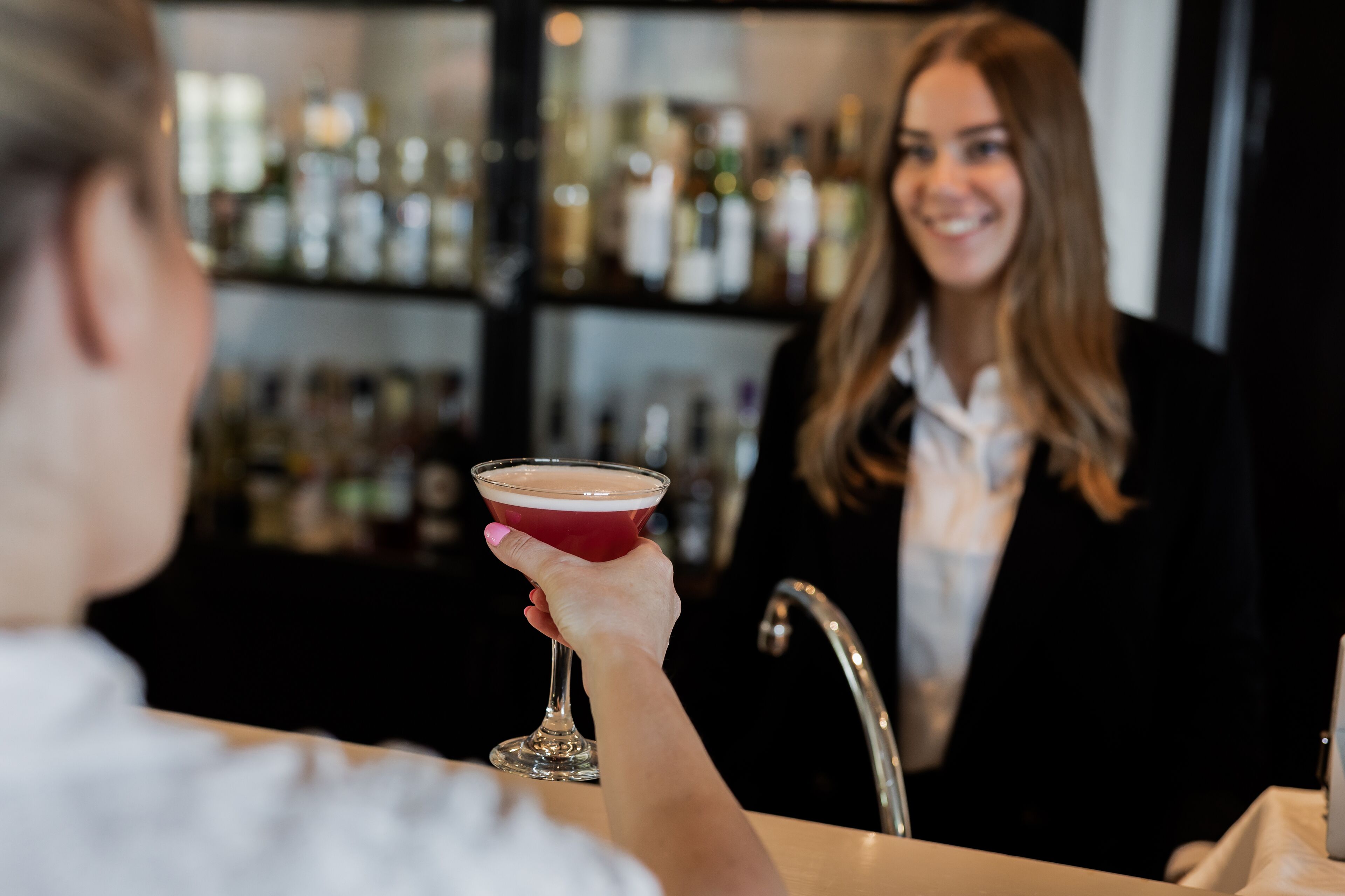 En bardisk med en person som håller i ett glas och en diskbänk i bakgrunden.