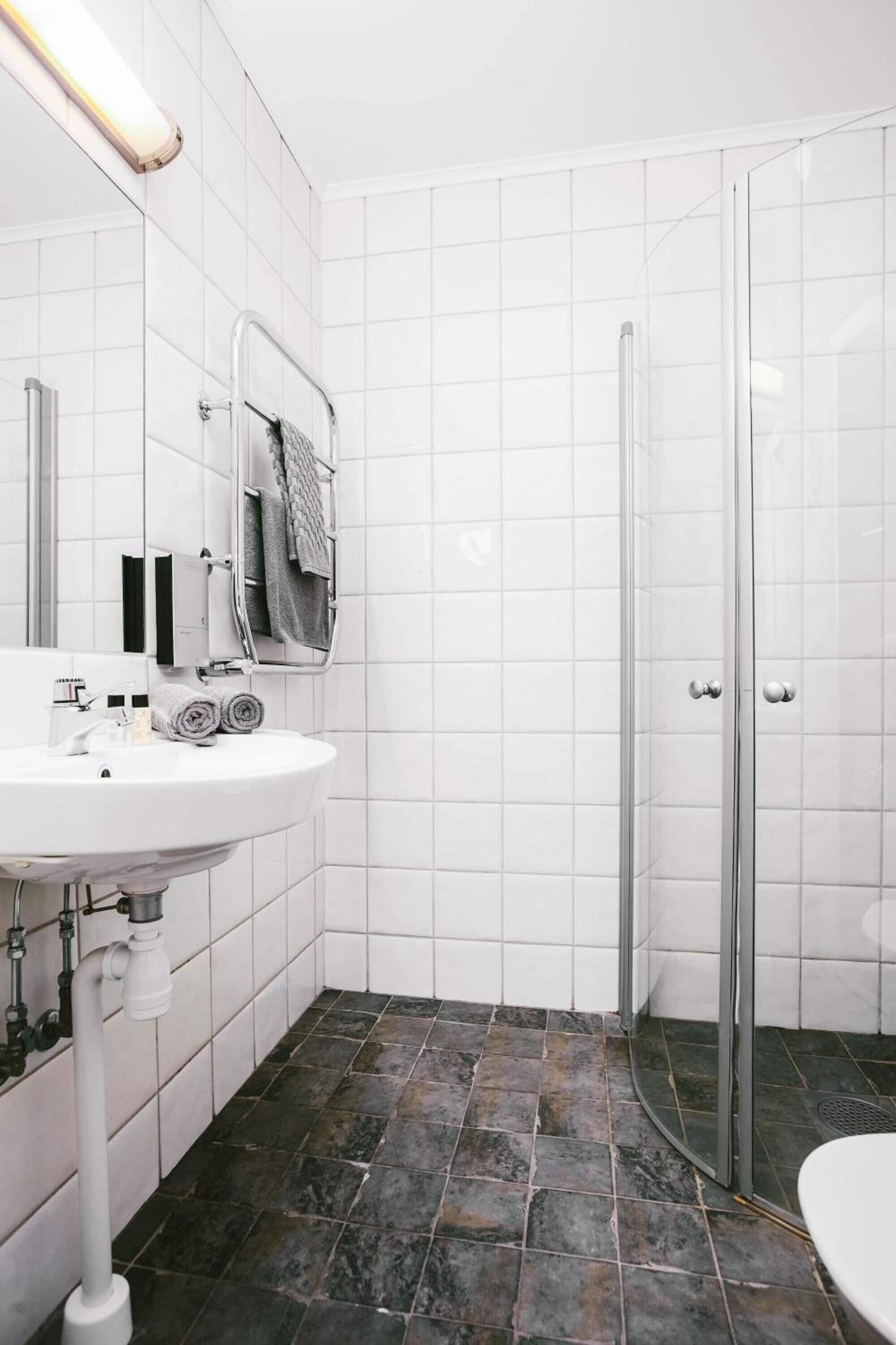 Un baño con lavamanos blanco, espejo y ducha.