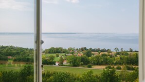 A view from a window overlooking a rural landscape with houses and a body of water. - Hotel Gyllene Uttern (Gränna)