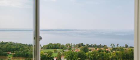 A view from a window overlooking a rural landscape with houses and a body of water.