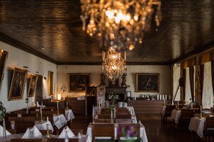 Un comedor con mesas dispuestas para el servicio, una araña y obras de arte en las paredes.