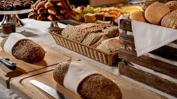 Une variété de pains et de viennoiseries sont disposés sur une table, notamment des pains complets et des croissants.