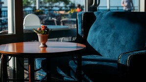 A blue upholstered chair and a small wooden table with a flower vase. - Hotel Gyllene Uttern (Gränna)