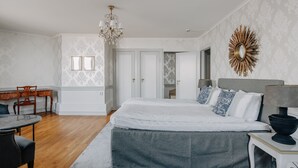 A bedroom with a large bed, a desk, and a chandelier. - Hotel Gyllene Uttern (Gränna)