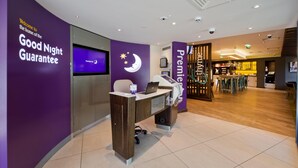 Een receptiebalie met een laptop, een incheckbalie en een muur met een bordje 'Good Night Guarantee'.