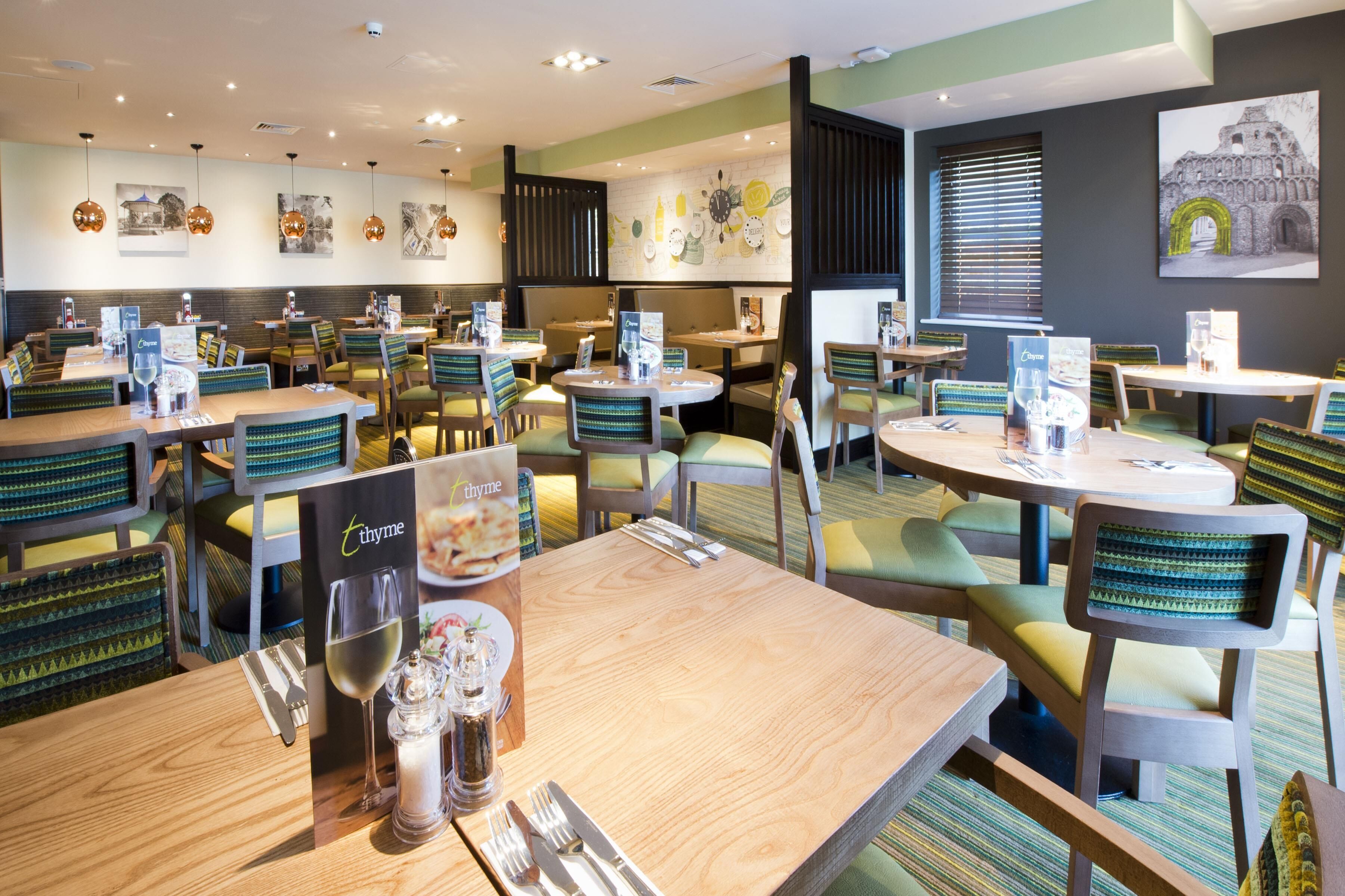 A restaurant with multiple tables and chairs, a menu stand, and wall art.