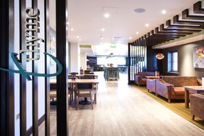 A modern interior with wooden flooring, a bar area, and seating arrangements. - Premier Inn Colchester Town Centre (Colchester)