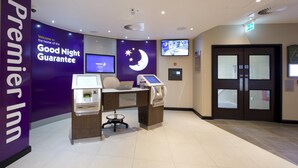 Un espace d’enregistrement comprenant un comptoir d’accueil, un kiosque en libre-service et un téléviseur fixé au mur.