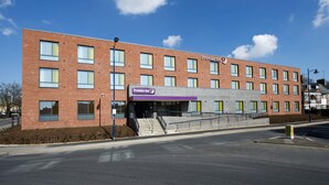 Un bâtiment en briques avec une enseigne « Premier Inn », de nombreuses fenêtres et un escalier menant à l’entrée.