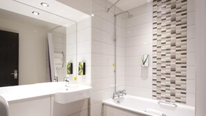 Une salle de bain moderne avec un grand miroir, un lavabo blanc, une baignoire et une douche.