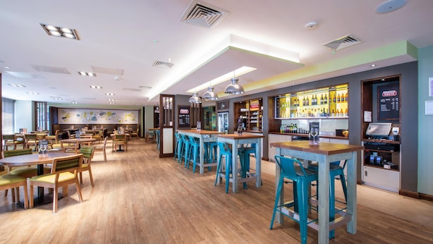 Ein modernes Restaurant mit Holzboden, Barhocker und einer Bar mit Costa-Karte.