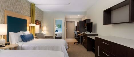 A hotel room with two beds, a desk, a TV, and a wardrobe.